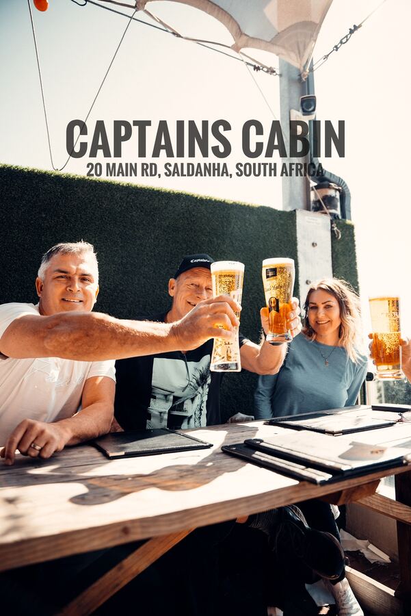 Three guests raising beers on the sunny deck at Captain's Cabin