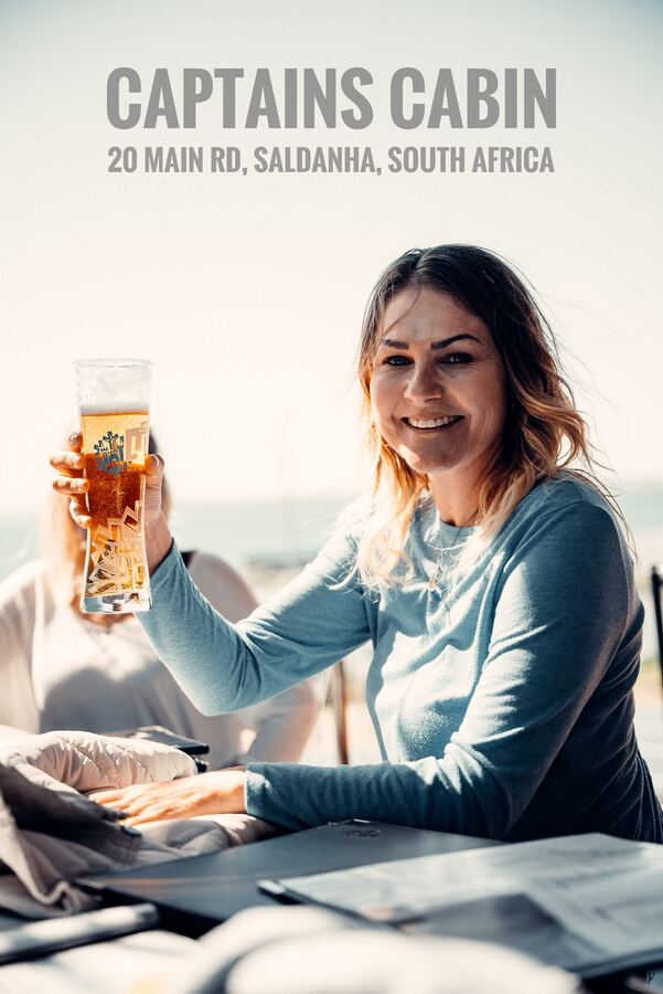 Guest raising a cold beer with the bay behind her